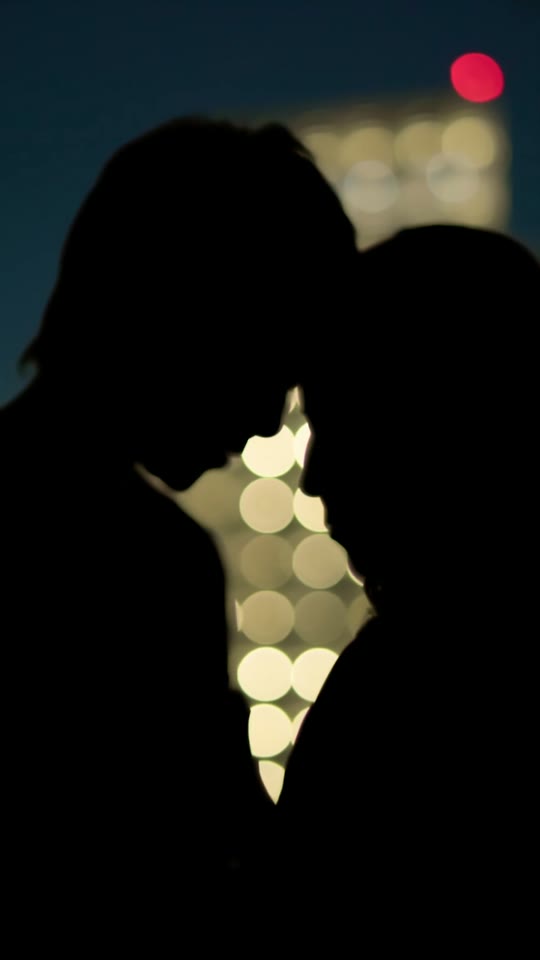Casal em silhueta sob luzes da cidade